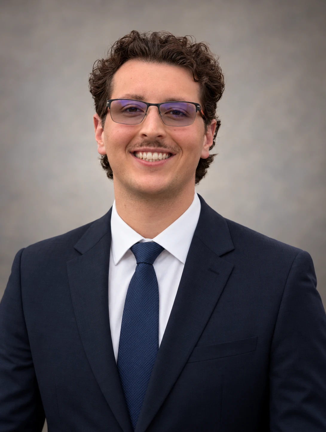 Adam Castleman, EA, smiling in a navy suit and tie